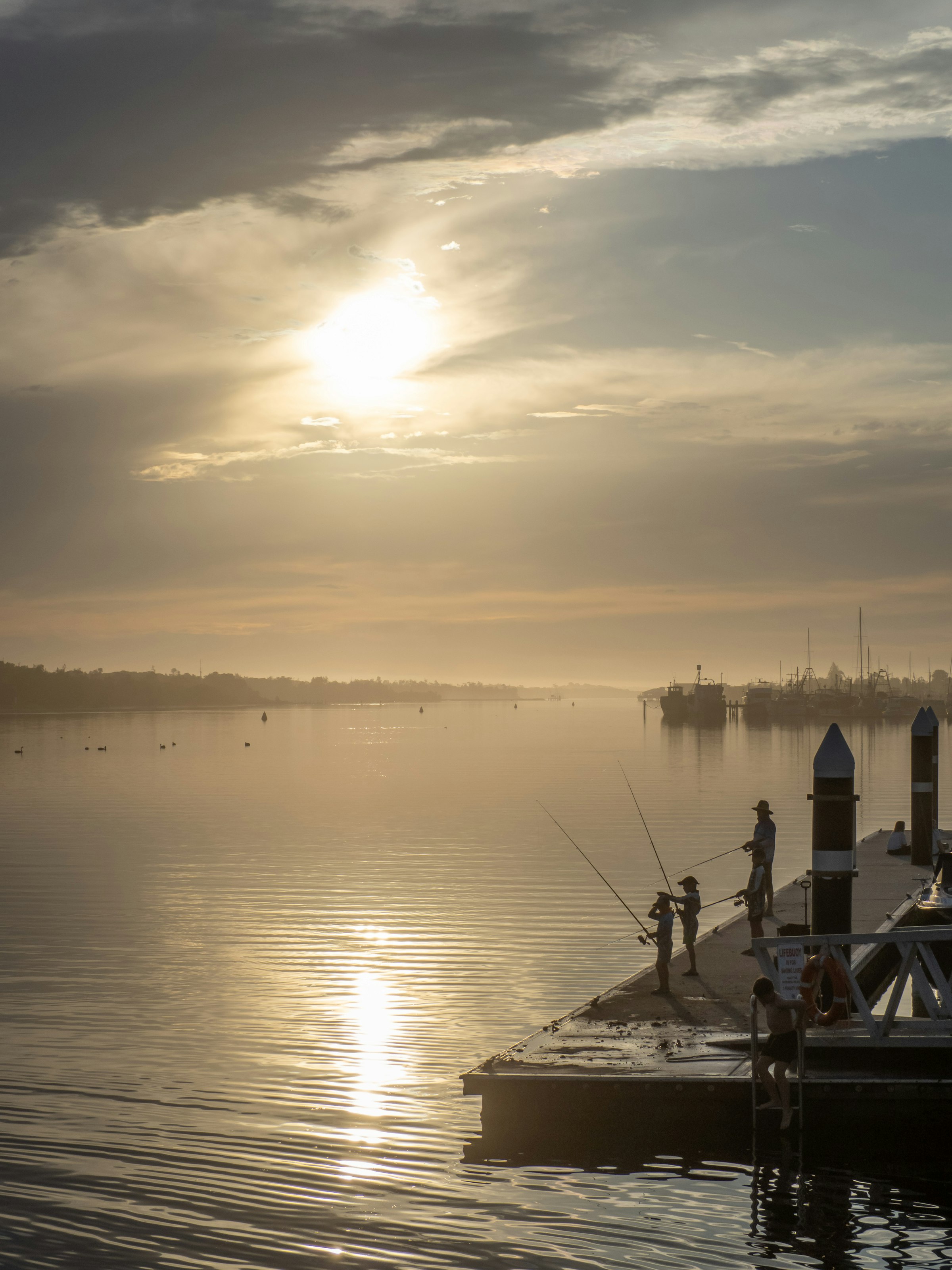 Anglers on a dock as the sun comes up over the water.