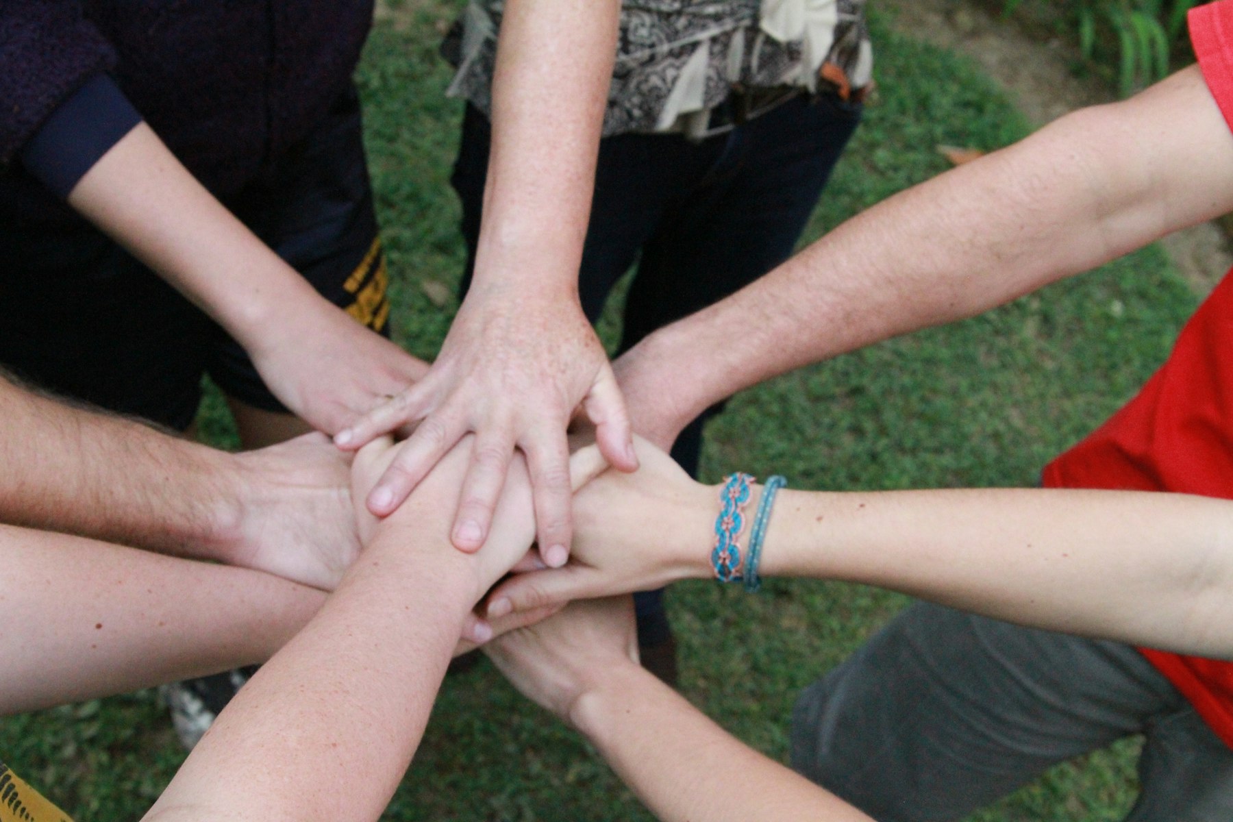 A group of people putting their hands together in a circle.