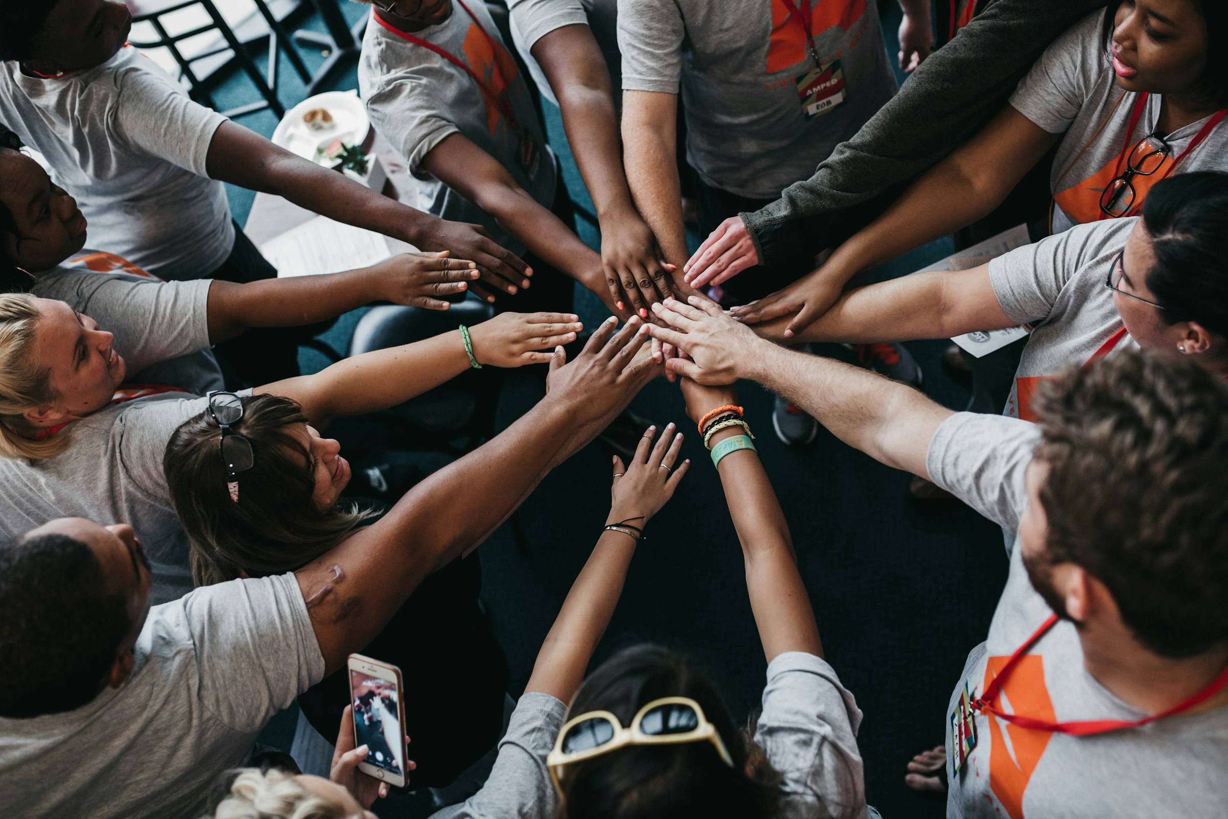 A circle of people reaching their hands in to the middle.