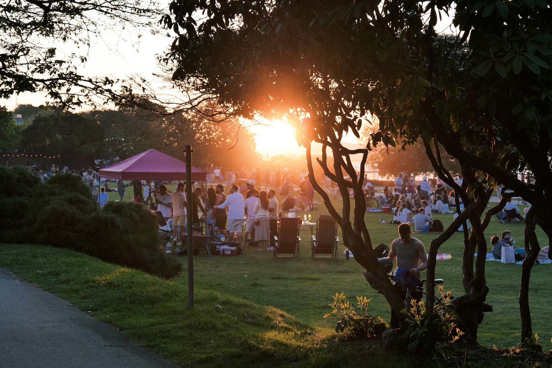 A community gathering in a park as the sun goes down.